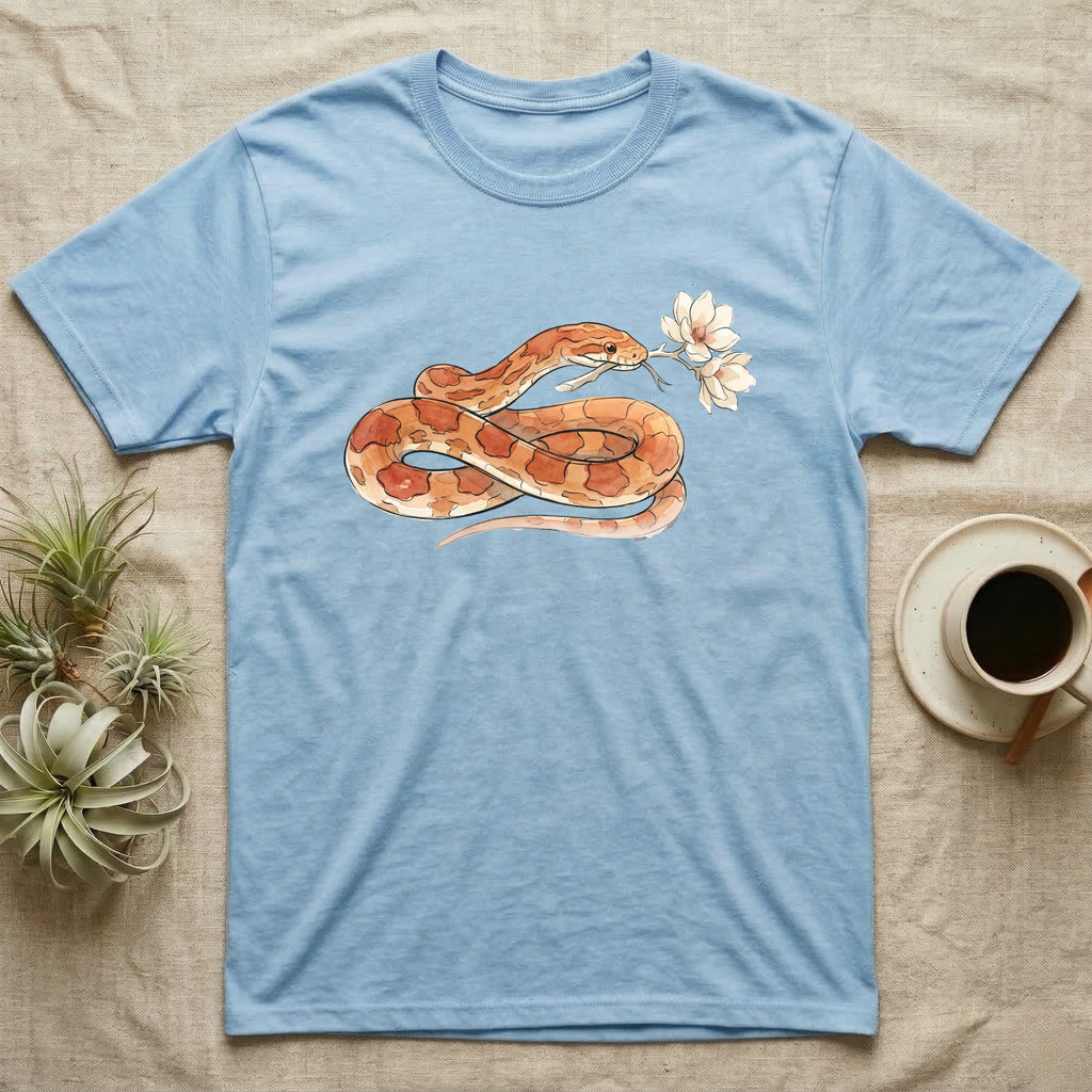Corn Snake Blossom T-Shirt in Light Blue — Watercolor illustration of an orange-and-cream corn snake holding a magnolia blossom sprig, on a dark grey t-shirt.