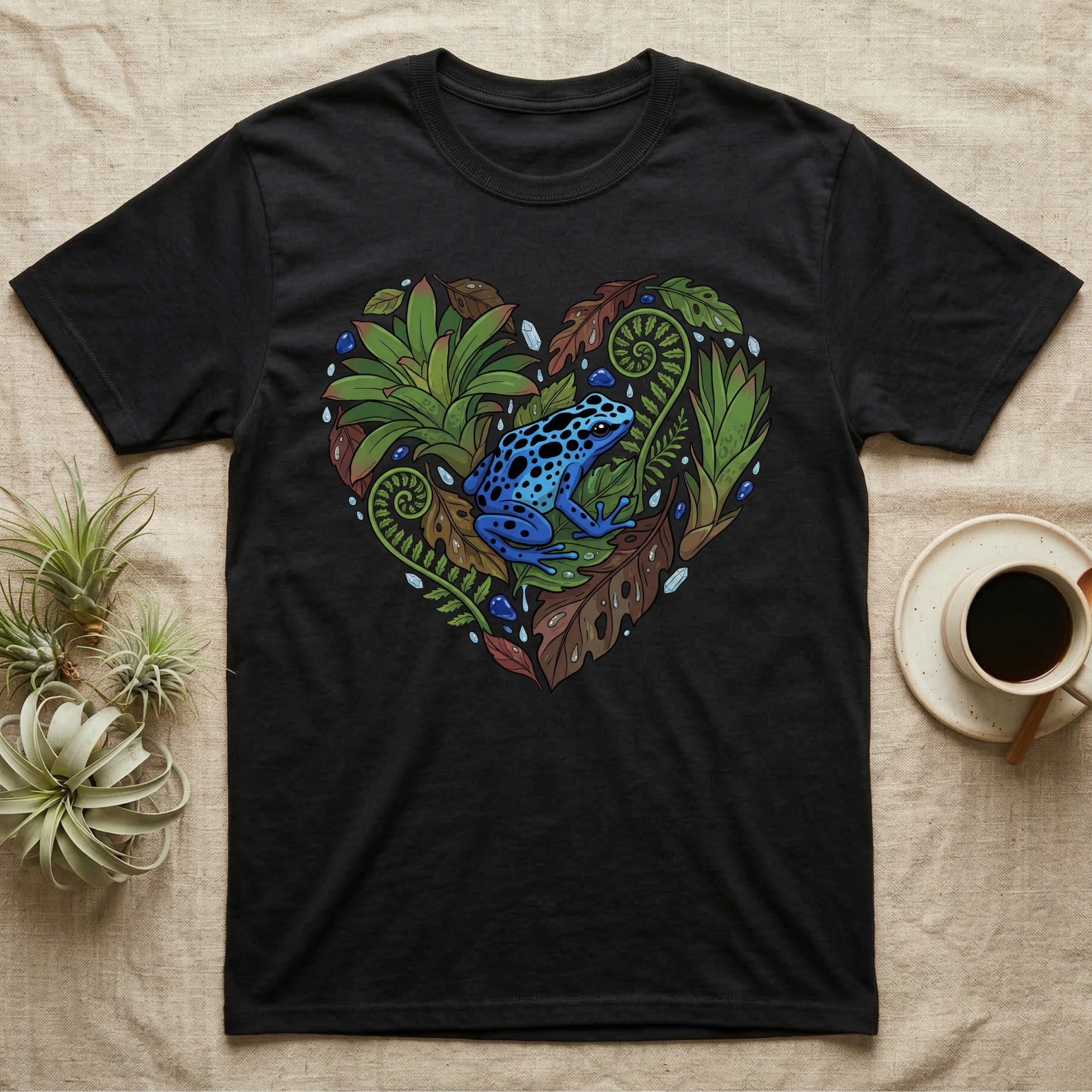 Black t-shirt with a heart-shaped arrangement of tropical leaves and a blue poison dart frog.