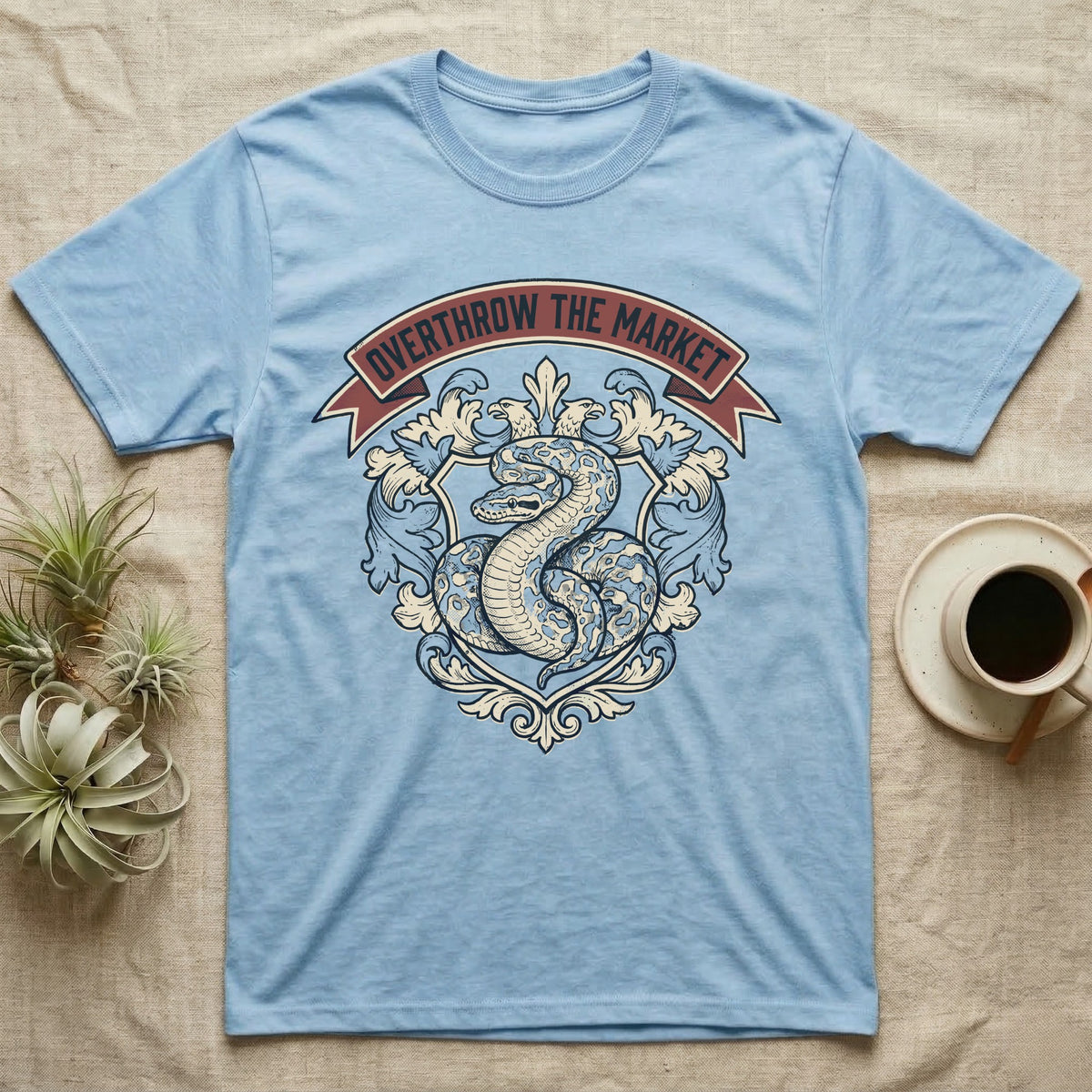 Overthrow The Market Python T-Shirt in Light Blue — Vintage heraldic-crest illustration of a regal ball python with a banner reading "Overthrow The Market."