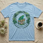 Light blue t-shirt featuring a frog on a mushroom within a leafy wreath.