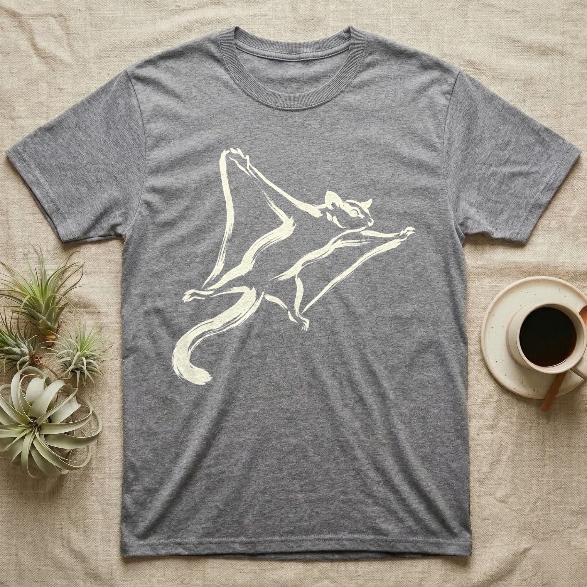 Gray t-shirt with a cream-colored drawing of a flying squirrel.