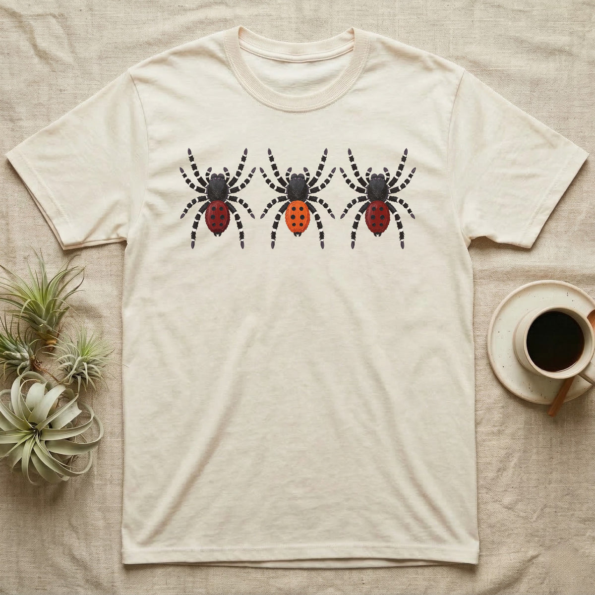 Velvet Spider Triptych T-Shirt in Natural — Three velvet spiders in a row, painted in thick impasto, each with a differently coloured red-and-black abdomen.