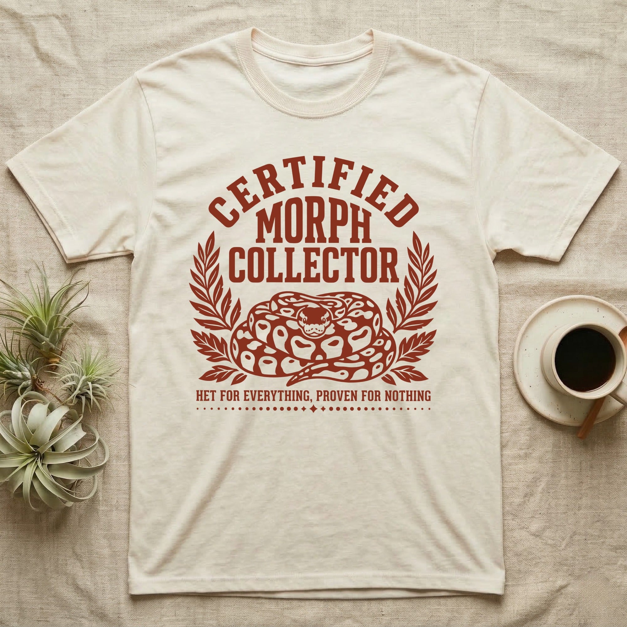 Ball Python Morph Crest T-Shirt in Natural — Linocut-style crest illustration of a coiled ball python with an arched "Certified Morph Collector" headline in rust ink.