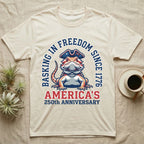 Bearded Dragon Basking T-Shirt in Natural — Sports-logo bearded dragon in a tricorn hat under a collegiate arch reading Basking in Freedom Since 1776.