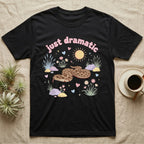 Western Hognose Snake Baby T-Shirt in Black — Pastel western hognose snake in a low coil with tongue out among grasses, puffy pink bubble wordmark "just dramatic" above.
