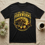 Gila Monster Hornworms Tee in Black — Bold gold and maroon woodcut tee of a Gila monster with banded tail, large text reading Don't Feed Me Hornworms, on black.