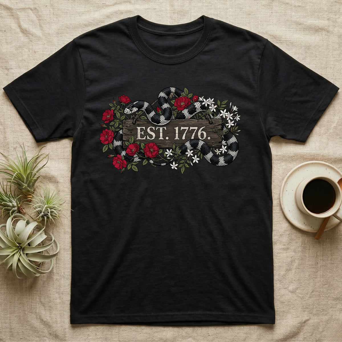 Kingsnake Floral 1776 T-Shirt in Black — Black-and-white California kingsnake woven through roses and jasmine around a wooden sign reading Est. 1776.