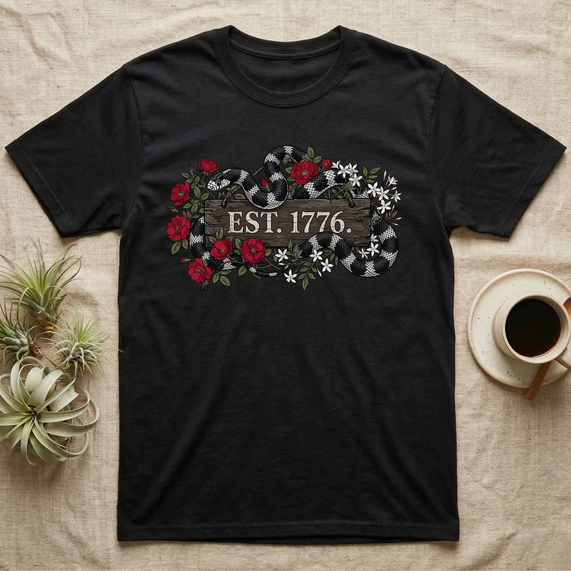 Kingsnake Floral 1776 T-Shirt in Black — Black-and-white California kingsnake woven through roses and jasmine around a wooden sign reading Est. 1776.