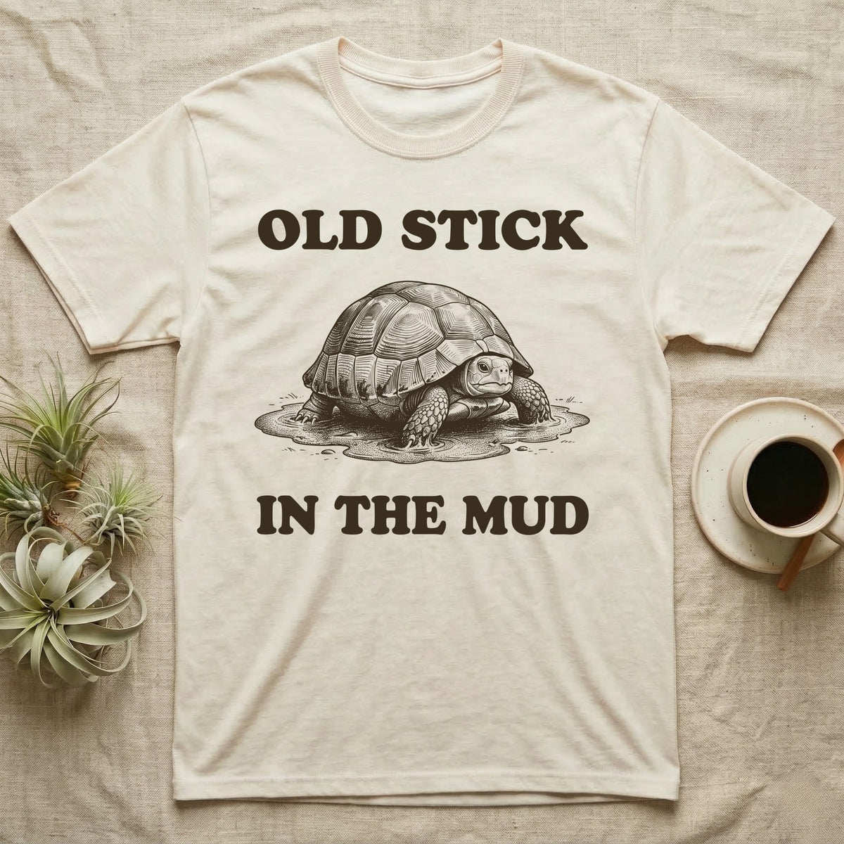 Hermann's Tortoise Mud T-Shirt in Natural — Engraved Hermann's tortoise sitting in a mud puddle, with the words Old Stick in the Mud