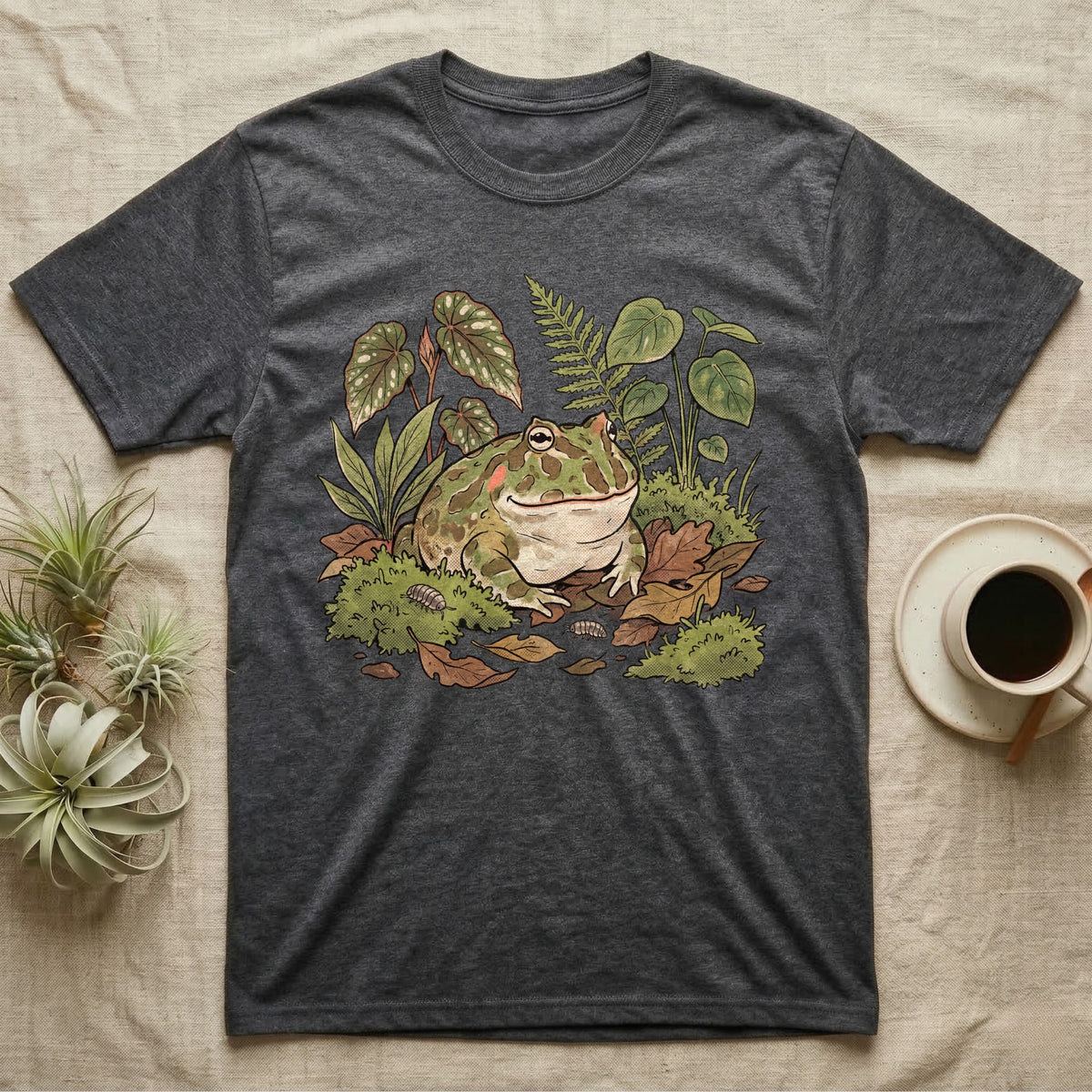 Bioactive Pacman Frog T-Shirt in Dark Heather — Warm botanical illustration of a content pacman frog half-buried in a lush bioactive habitat of moss and leaf litter.