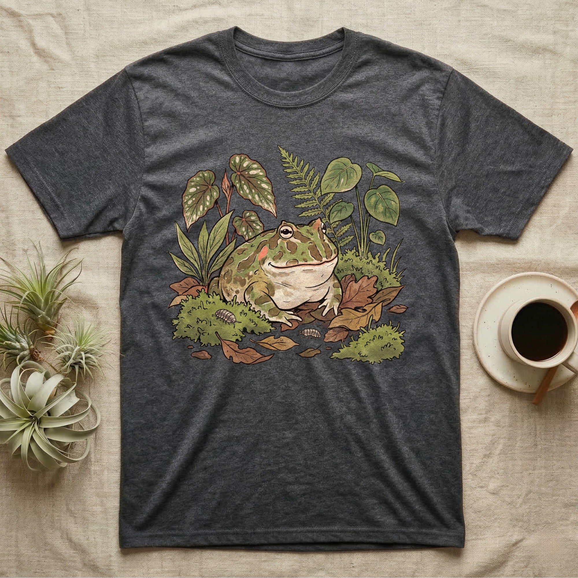 Bioactive Pacman Frog T-Shirt in Dark Heather — Warm botanical illustration of a content pacman frog half-buried in a lush bioactive habitat of moss and leaf litter.