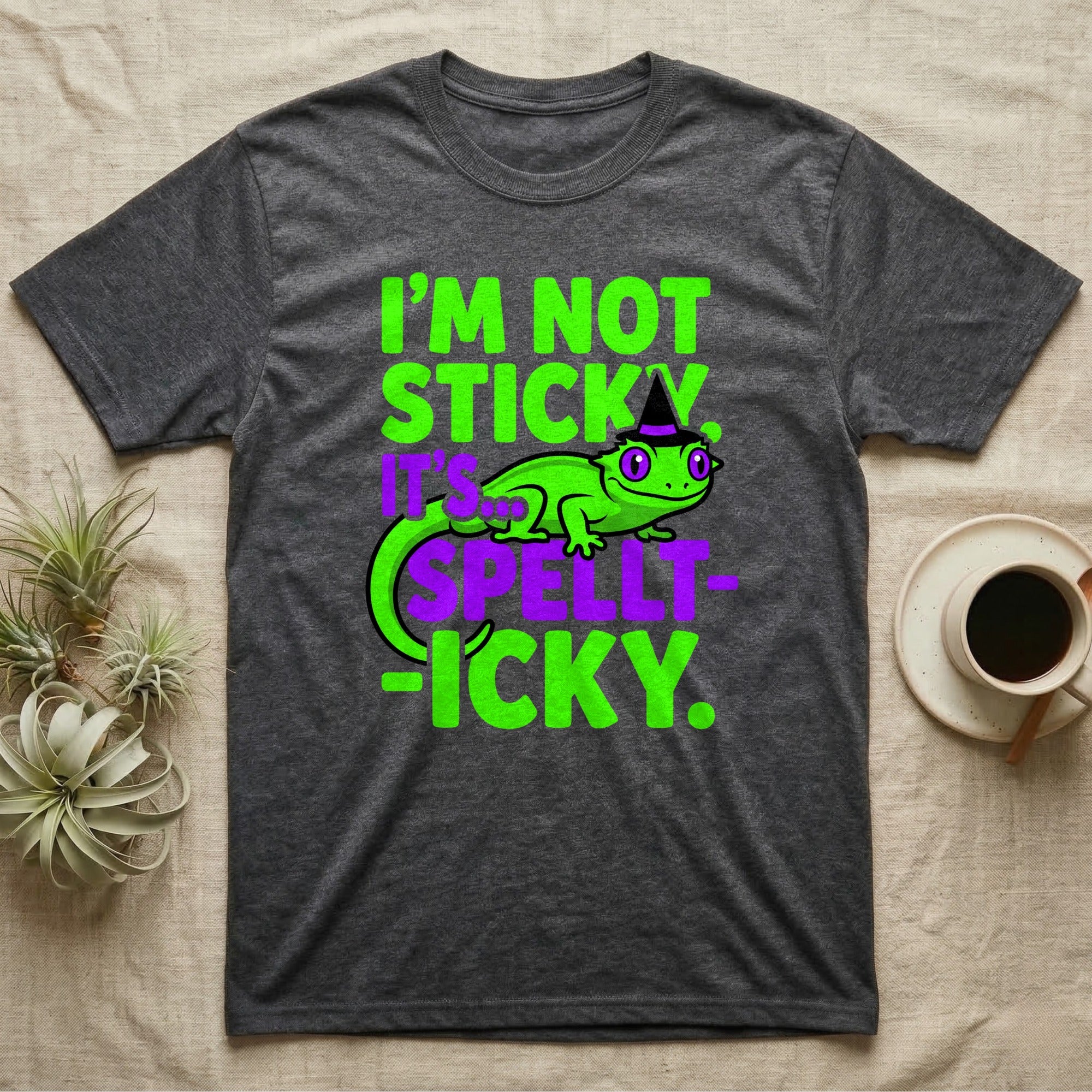 Crested Gecko Spellt-icky T-Shirt in Dark Heather — Neon cartoon crested gecko in a witch hat with stacked text, "I'm Not Sticky, It's Spellt-icky."