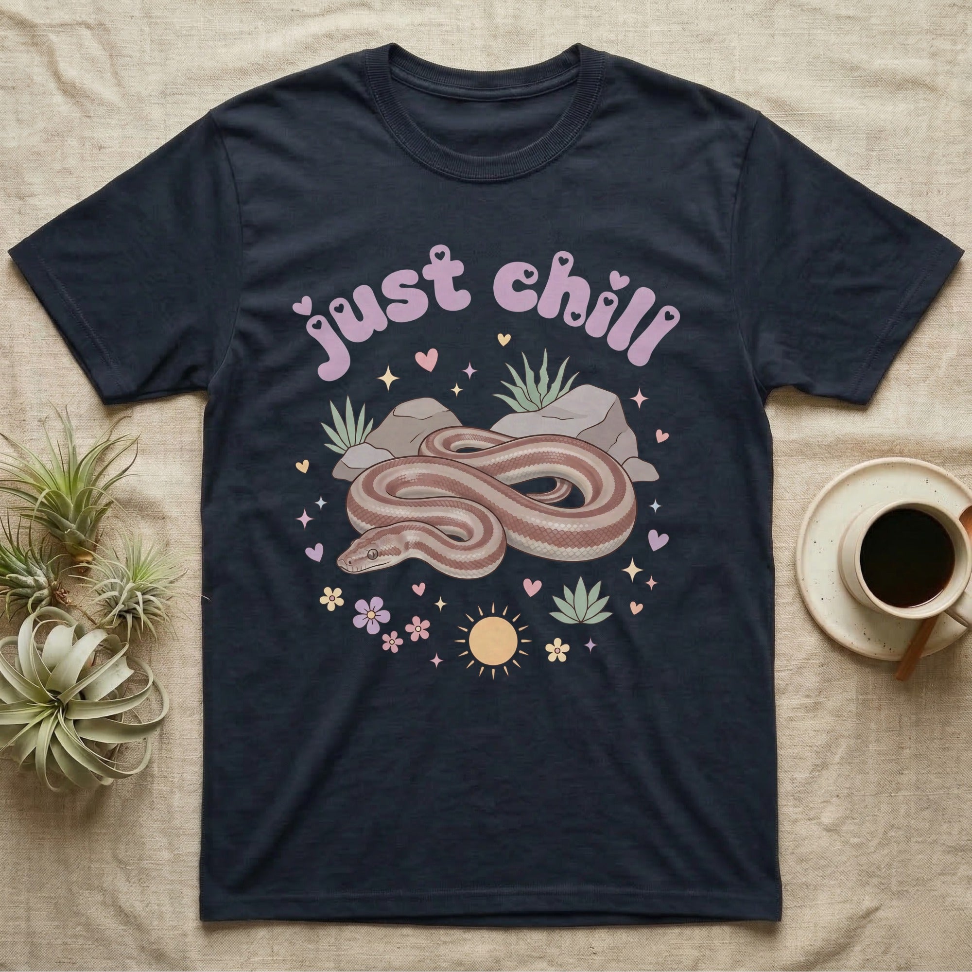 Rosy Boa Softie T-Shirt in Navy — Relaxed coiled rosy boa with sleepy eyes under pastel bubble text "just chill" with tiny hearts.