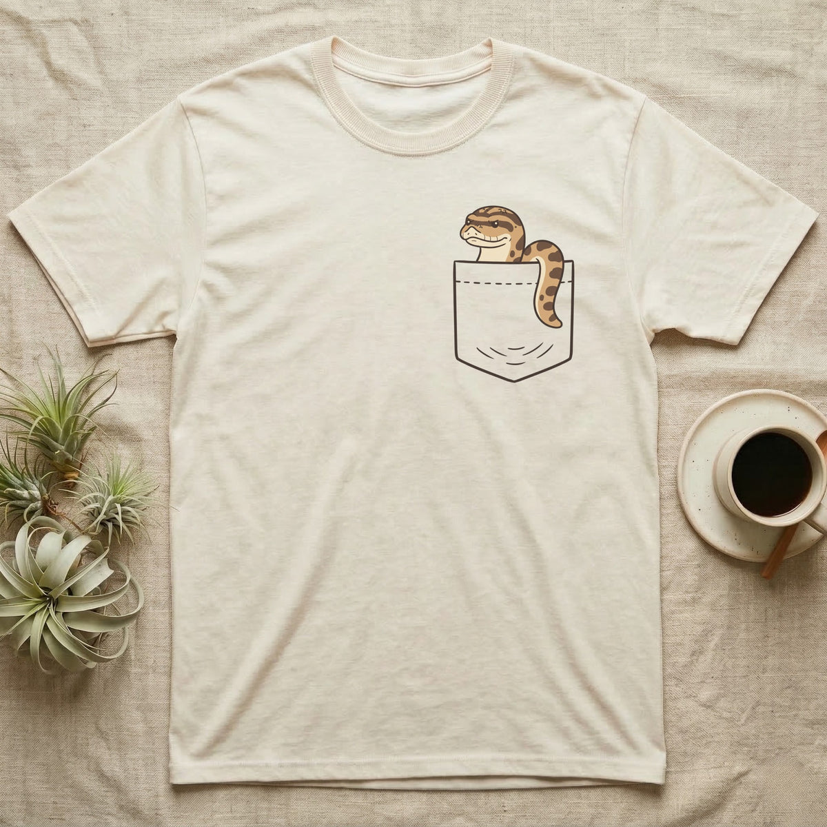 Hognose Pocket T-Shirt in Natural — Cartoon western hognose with an upturned snout peeking out of a chest pocket, its body looped over the edge