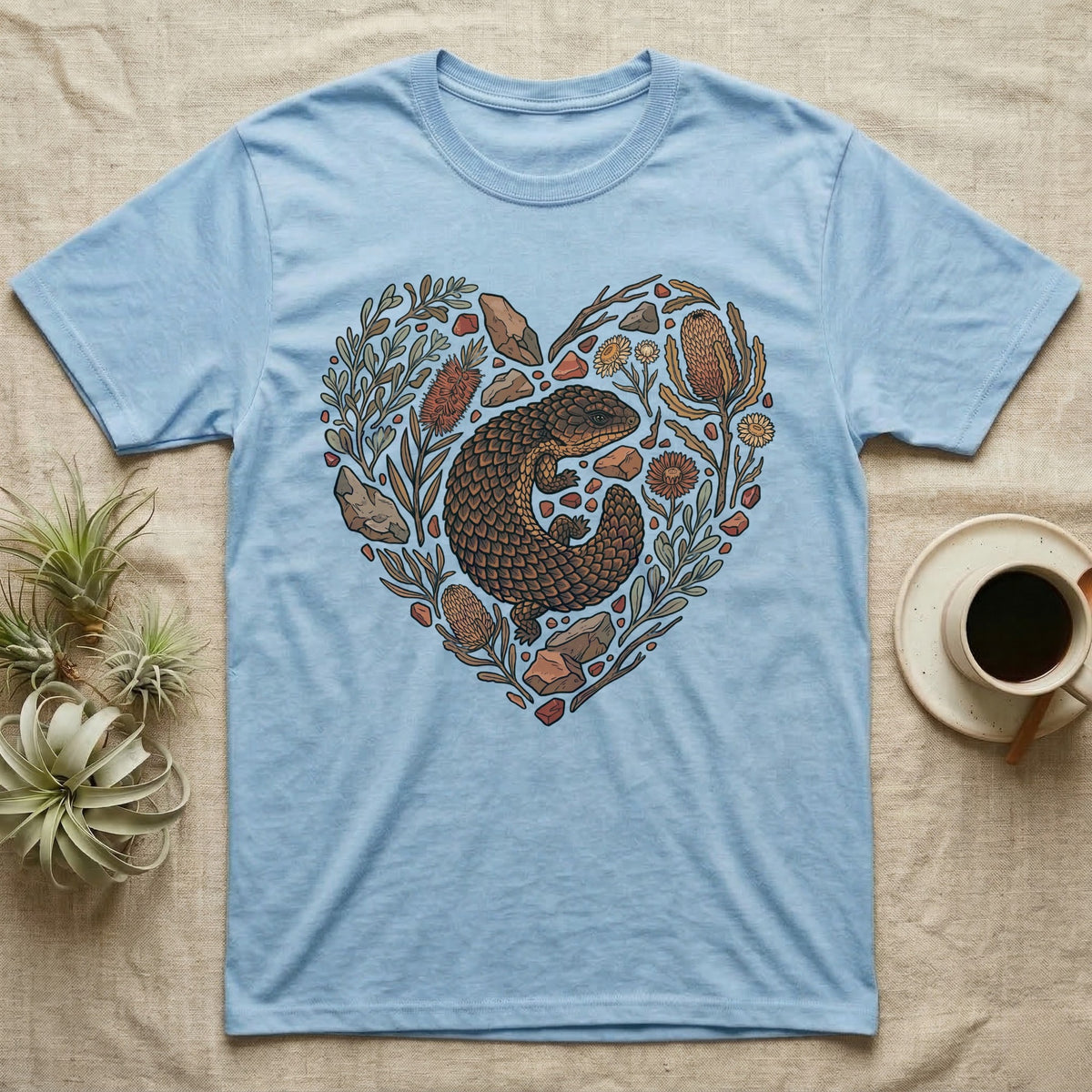 Blue t-shirt with a heart-shaped design of a thorny devil and Australian flora.