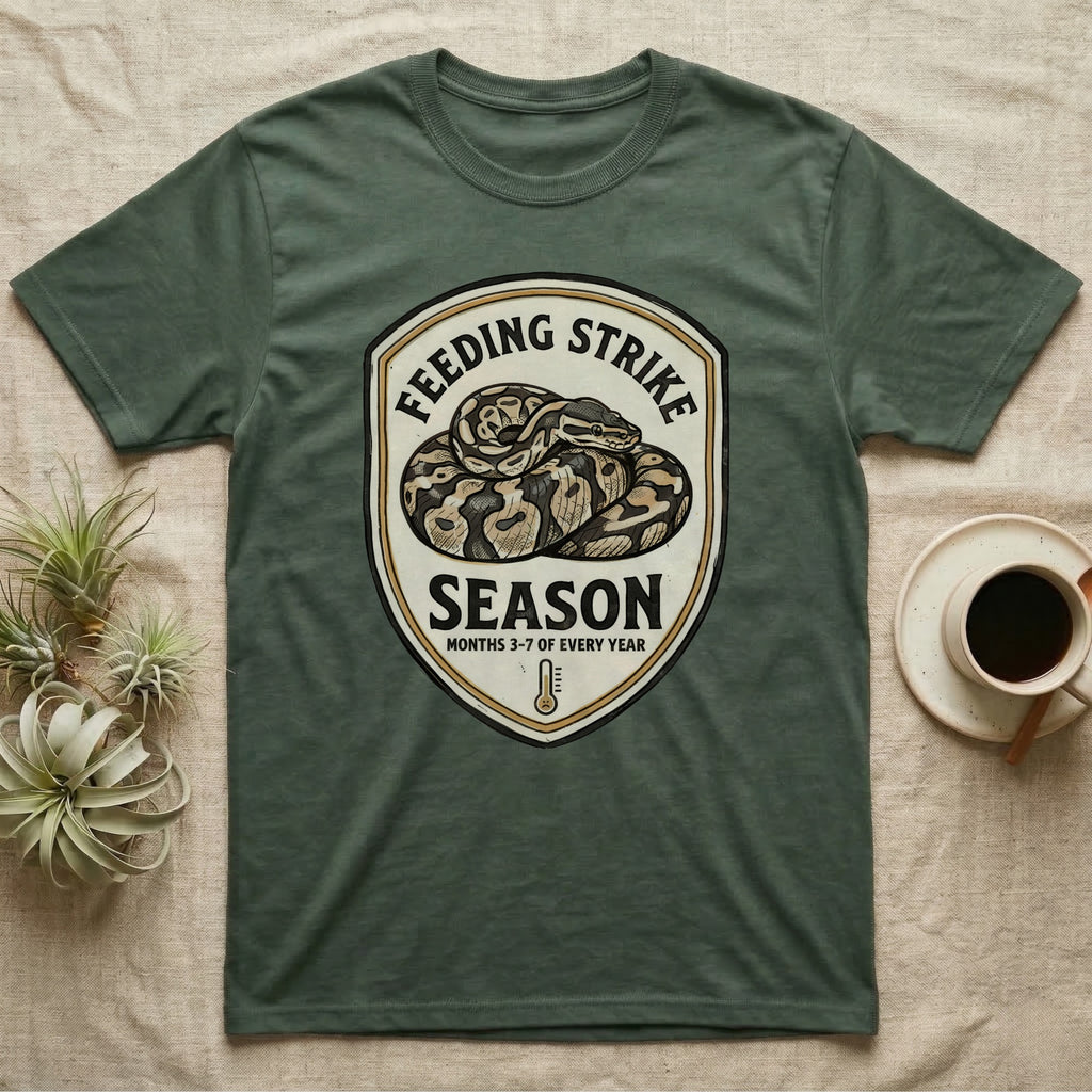 Ball Python Feeding Strike T-Shirt in Military Green — Vintage-ink badge of a coiled ball python with carved type "Feeding Strike Season" and fine print "Months 3-7 Of Every Year."