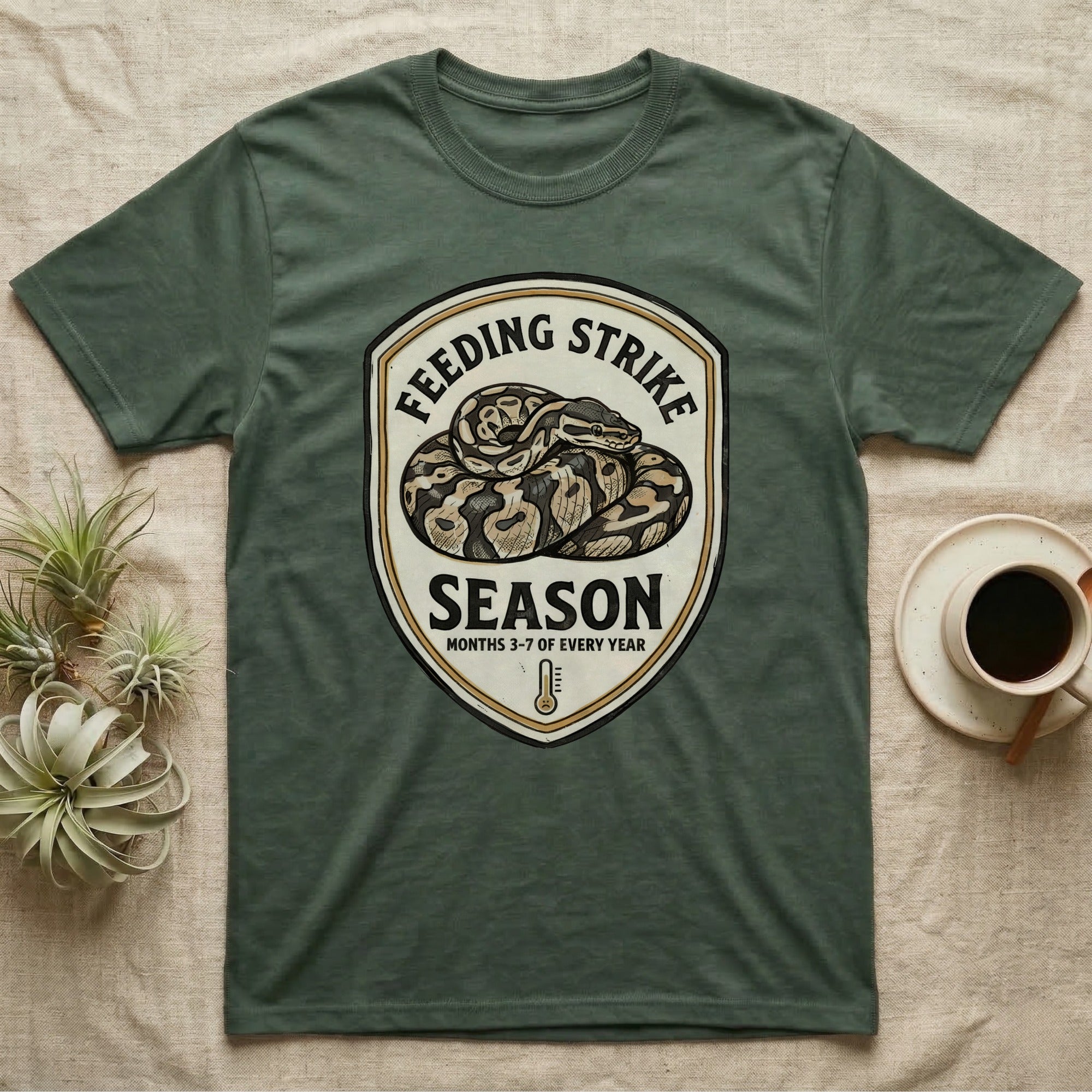 Ball Python Feeding Strike T-Shirt in Military Green — Vintage-ink badge of a coiled ball python with carved type "Feeding Strike Season" and fine print "Months 3-7 Of Every Year."