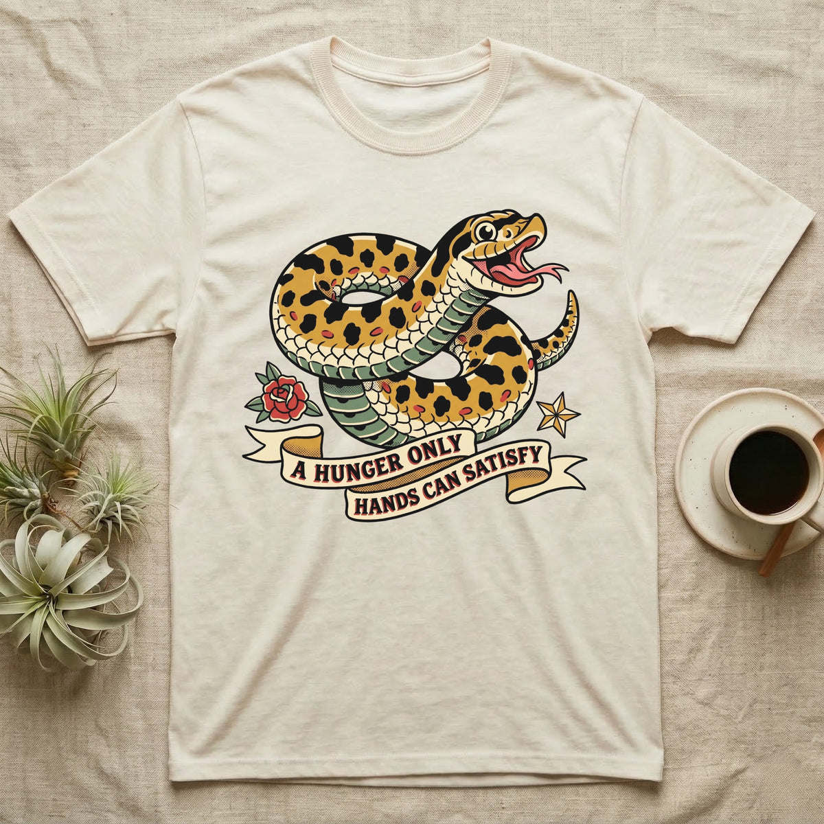 Hognose Hunger Flash T-Shirt in Natural — American-traditional tattoo-flash illustration of a hognose snake in a heroic coil with a banner reading the feeding-hunger line.