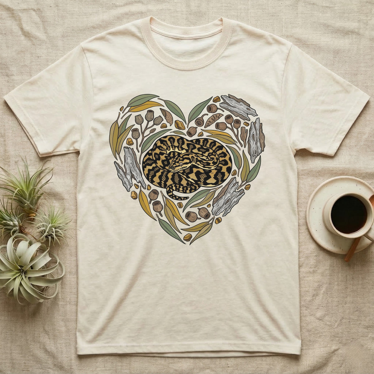 Cream t-shirt with a heart-shaped illustration of a coiled snake and natural elements.