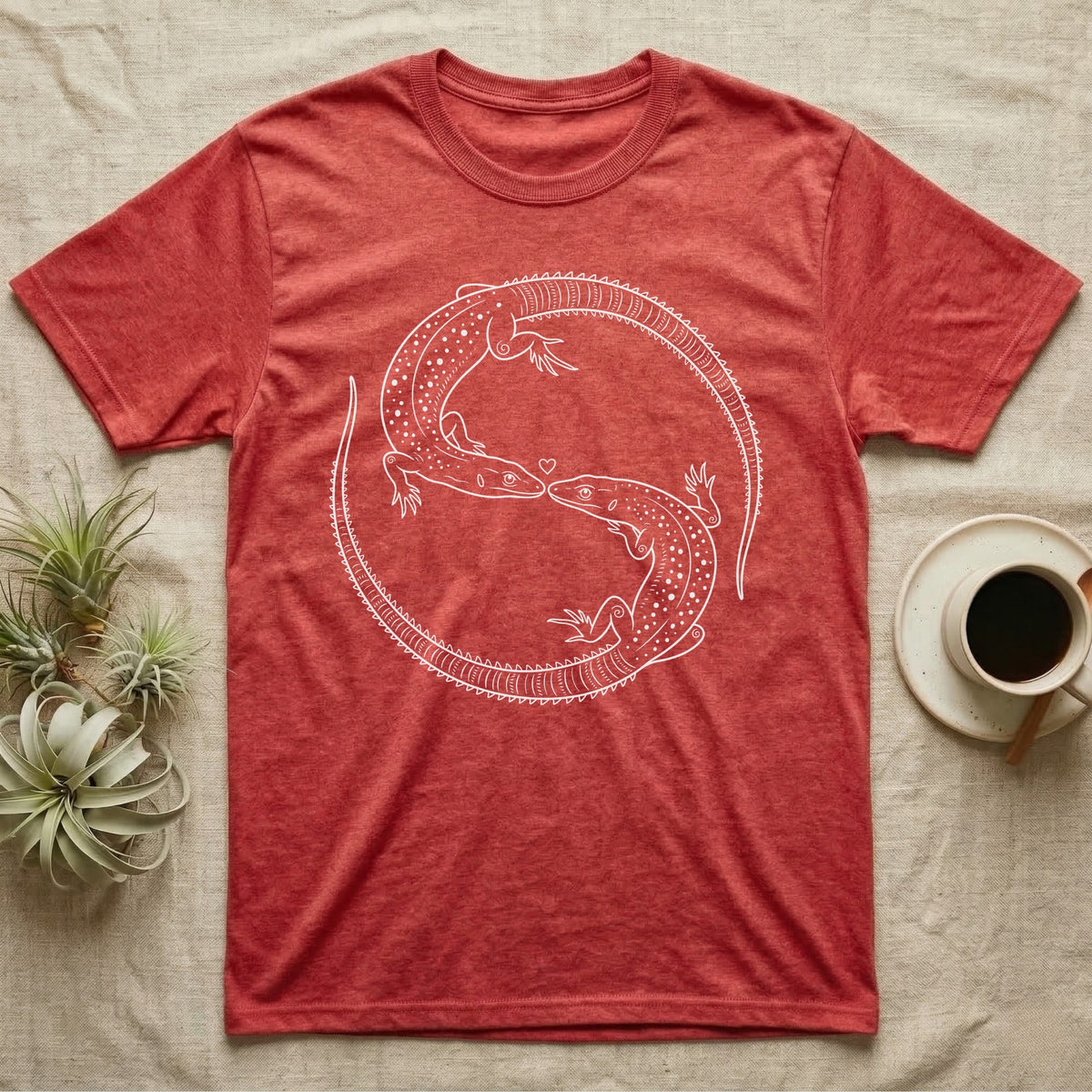 Ackie Monitor Roundel T-Shirt in Heather Red — Two ackie monitors in fine white line art, mirrored at 180 degrees around a tiny heart, tails sweeping outward.