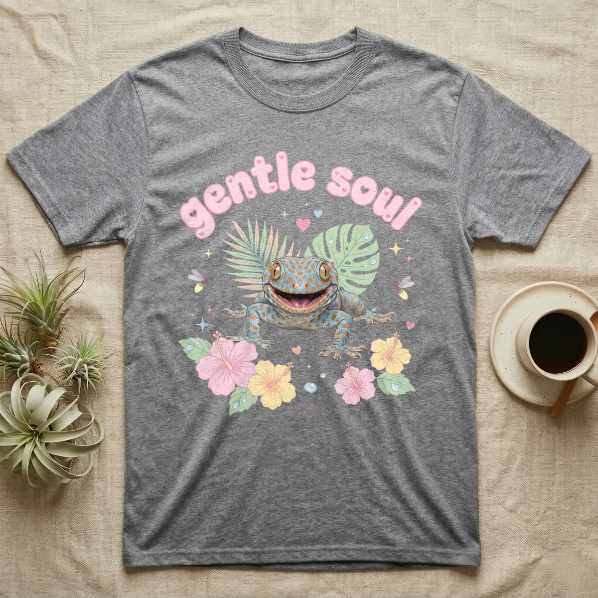 Tokay Gecko Baby T-Shirt in Sport Grey — Blue-and-orange spotted tokay gecko among pastel leaves and hibiscus under puffy pink bubble text "gentle soul".