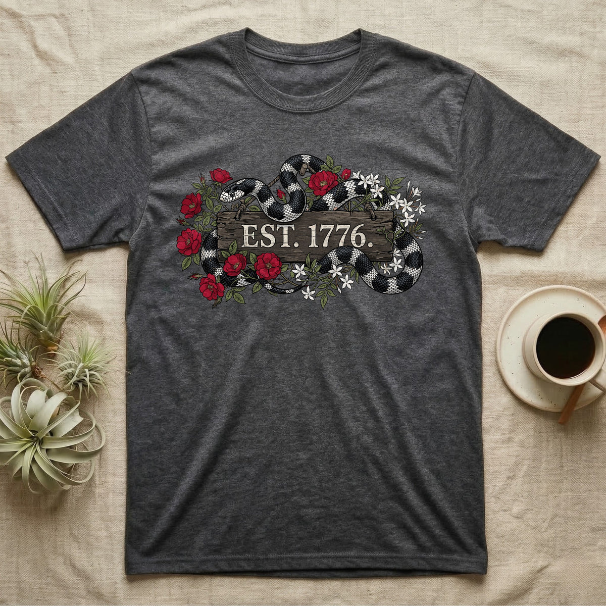 Kingsnake Floral 1776 T-Shirt in Dark Heather — Black-and-white California kingsnake woven through roses and jasmine around a wooden sign reading Est. 1776.