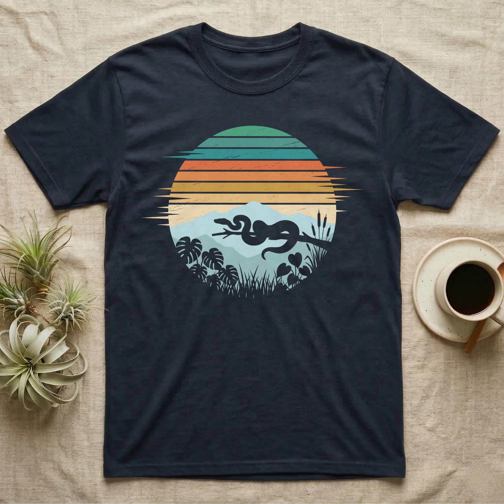 Ball Python Retro Sunset T-Shirt in Navy — Ball python silhouette draped over a branch inside a retro striped sunset disc with monstera leaves on a tee