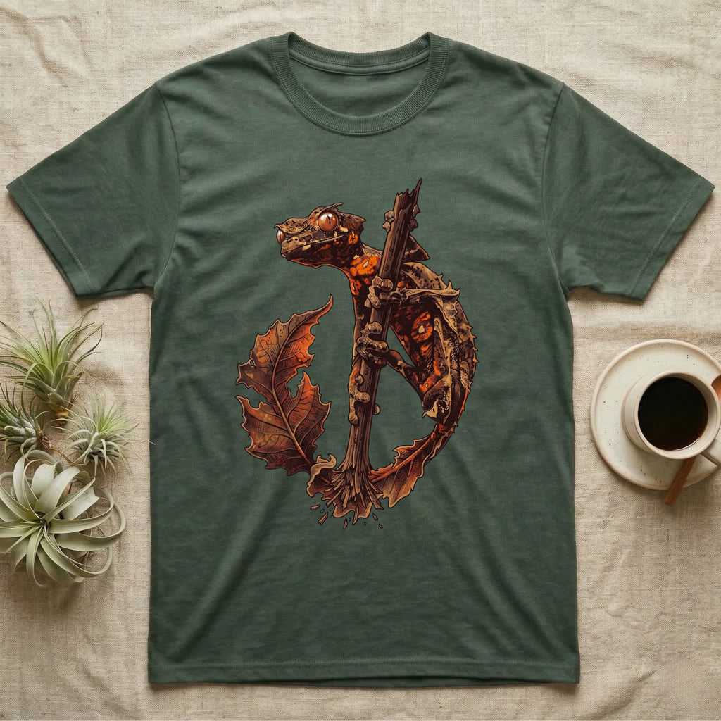 Vintage ink illustration of an eyelash leaf-tailed gecko clinging to a branch with its tail curled beside a serrated leaf, no on-shirt text. — shown on a Military Green tee.