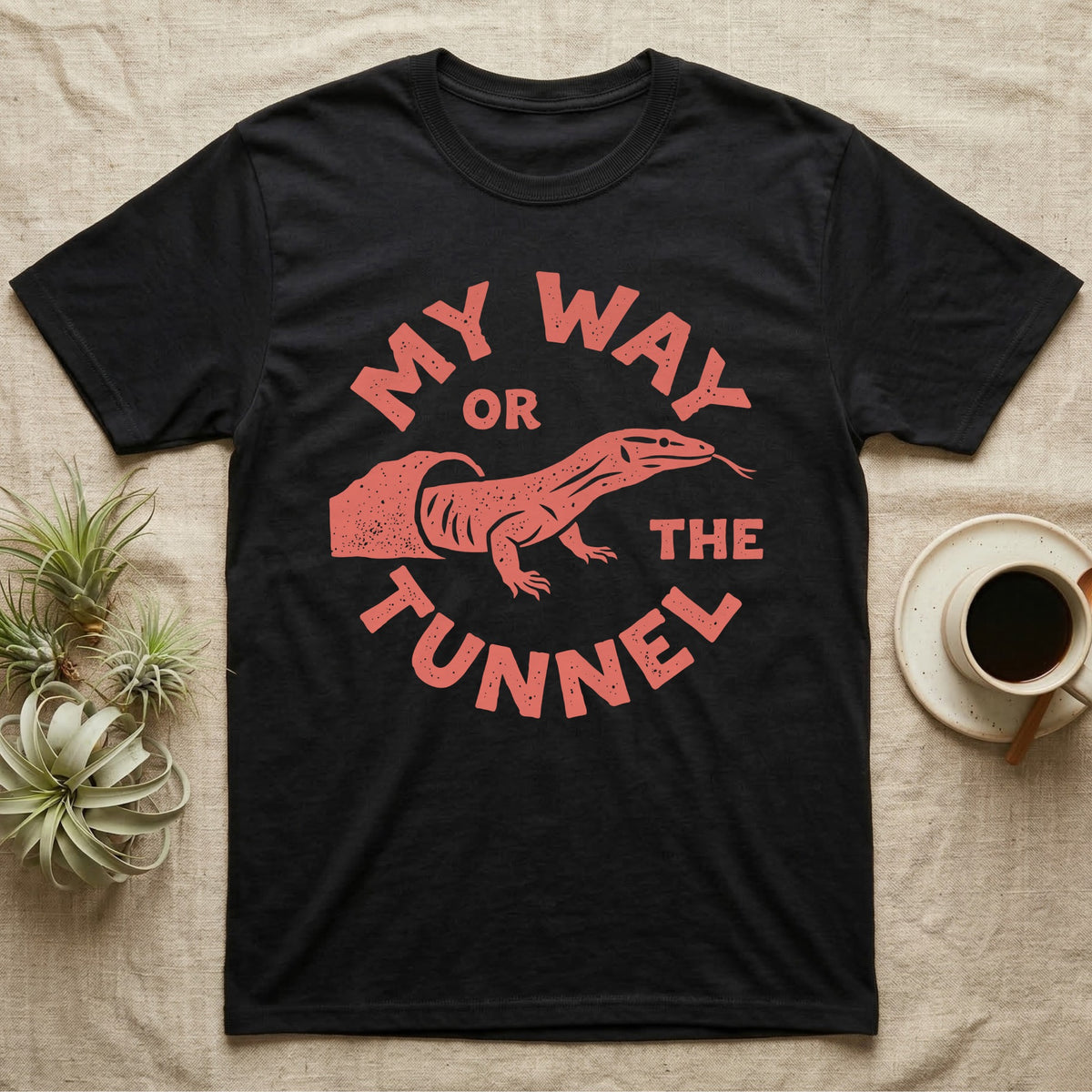 Ackie Monitor Tunnel T-Shirt in Black — Carved one-ink badge of an ackie monitor emerging from its sand tunnel, tongue out, ringed by the words MY WAY OR THE TUNNEL