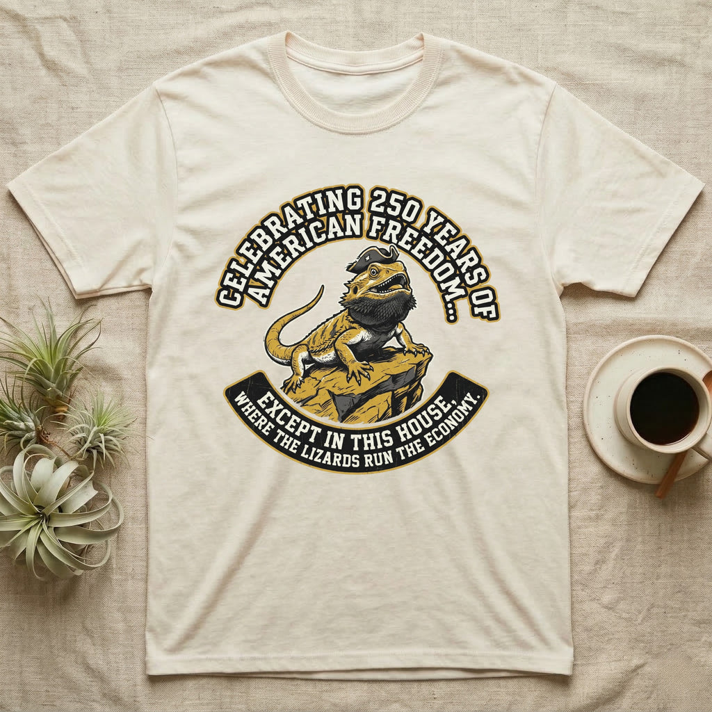 Bearded Dragon 1776 T-Shirt in Natural — Bold woodcut tee of a bearded dragon in a tricorn hat black-bearding on a rock, gold and cream banner reading the lizards run the economy.