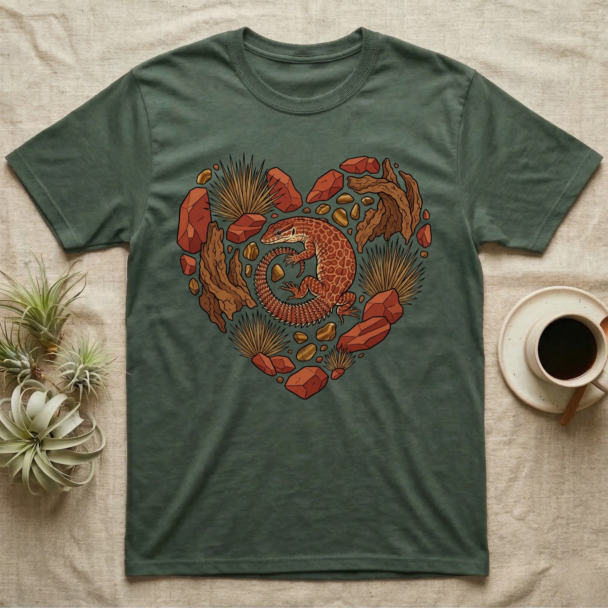 Heart-shaped design with a lizard and desert elements on a dark green t-shirt.