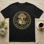 Black t-shirt with a circular design of a frog and mushroom, text reads "Small, Damp, & Happy".