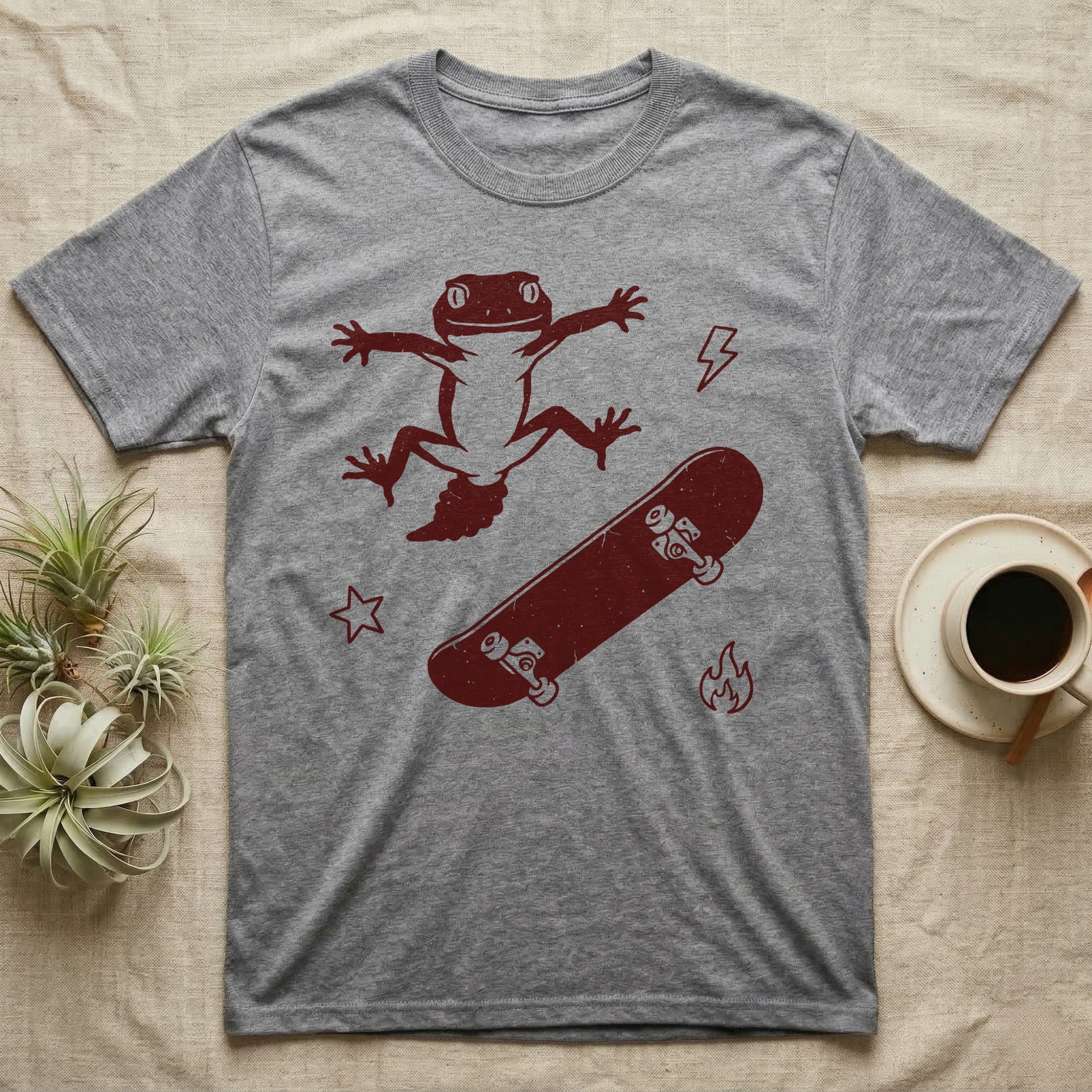 Knob-Tailed Gecko Kickflip T-Shirt in Sport Grey — Distressed one-ink illustration of a knob-tailed gecko airborne mid-kickflip above a tumbling skateboard.