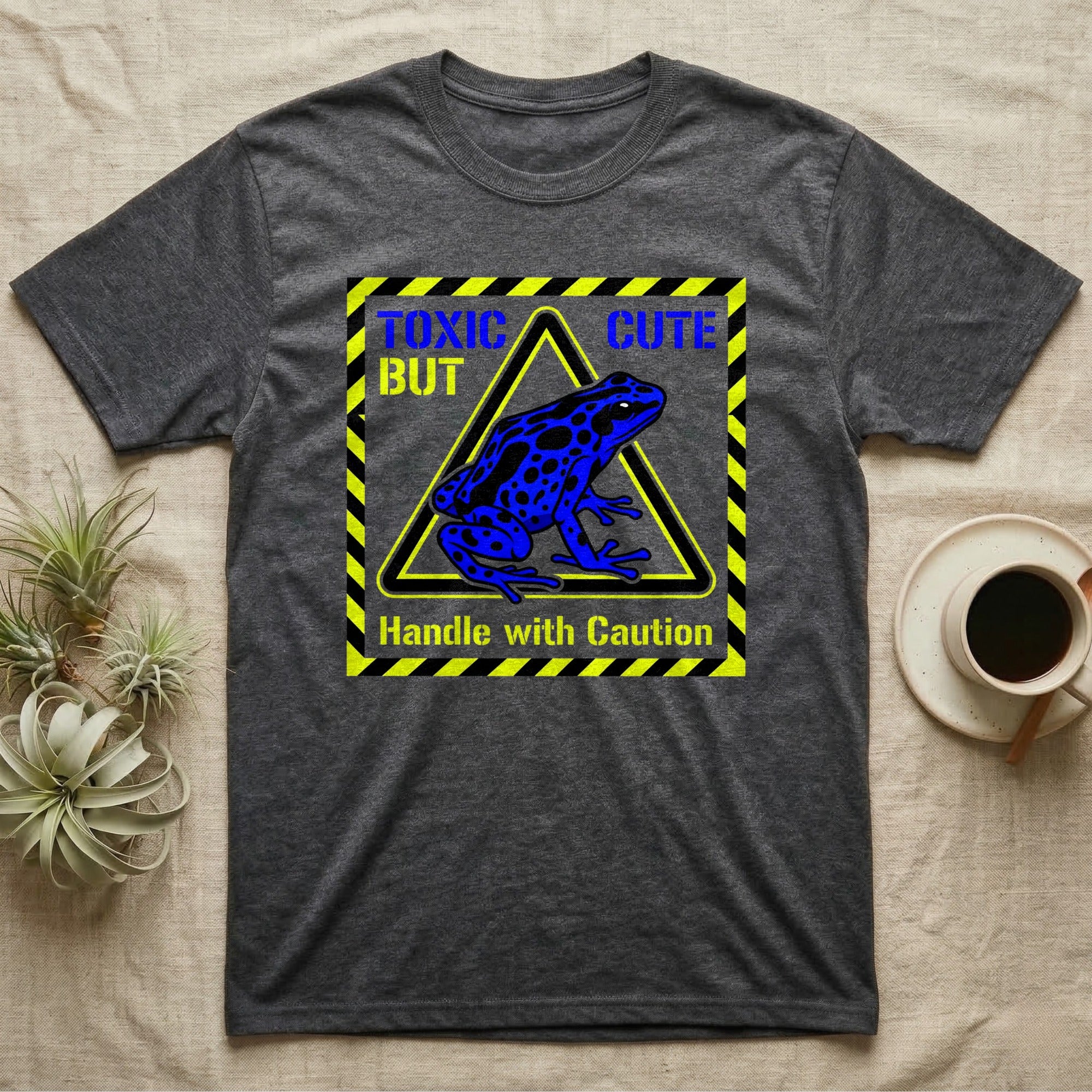 Dark grey t-shirt with blue poison dart frog graphic and "TOXIC BUT CUTE" text.