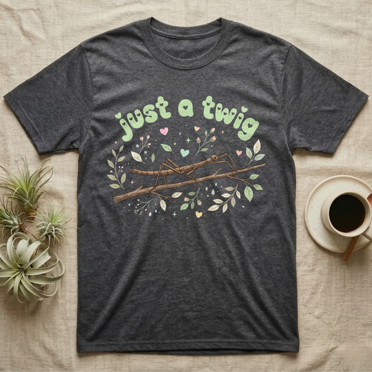 Stick Insect Softie T-Shirt in Dark Heather — Camouflaged stick insect on a branch under pastel bubble text "just a twig" with tiny hearts.