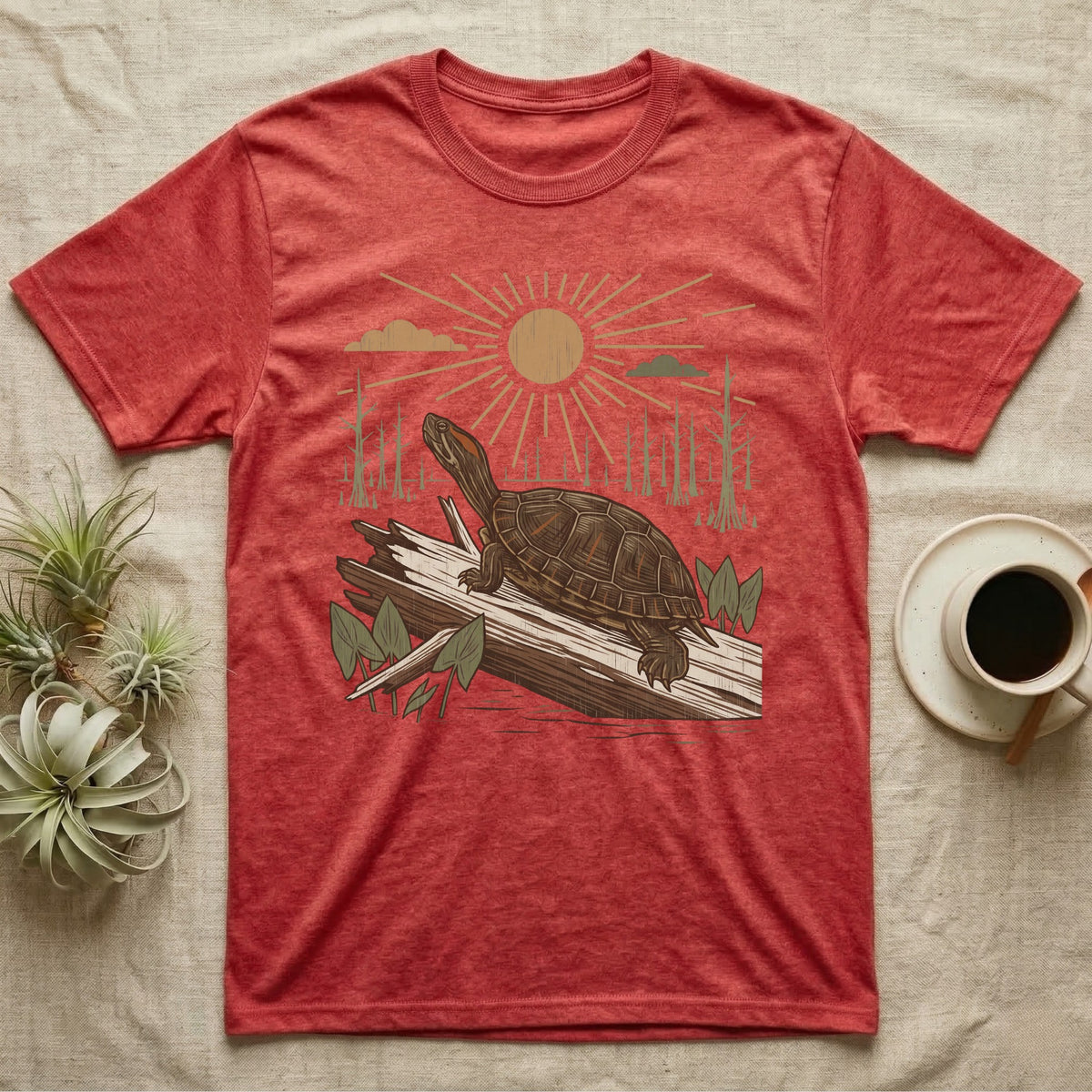 Red-Eared Slider Home Range T-Shirt in Heather Red — Woodcut-style illustration of a red-eared slider basking on a half-sunk log in a cypress swamp under a full sun, no on-shirt text.