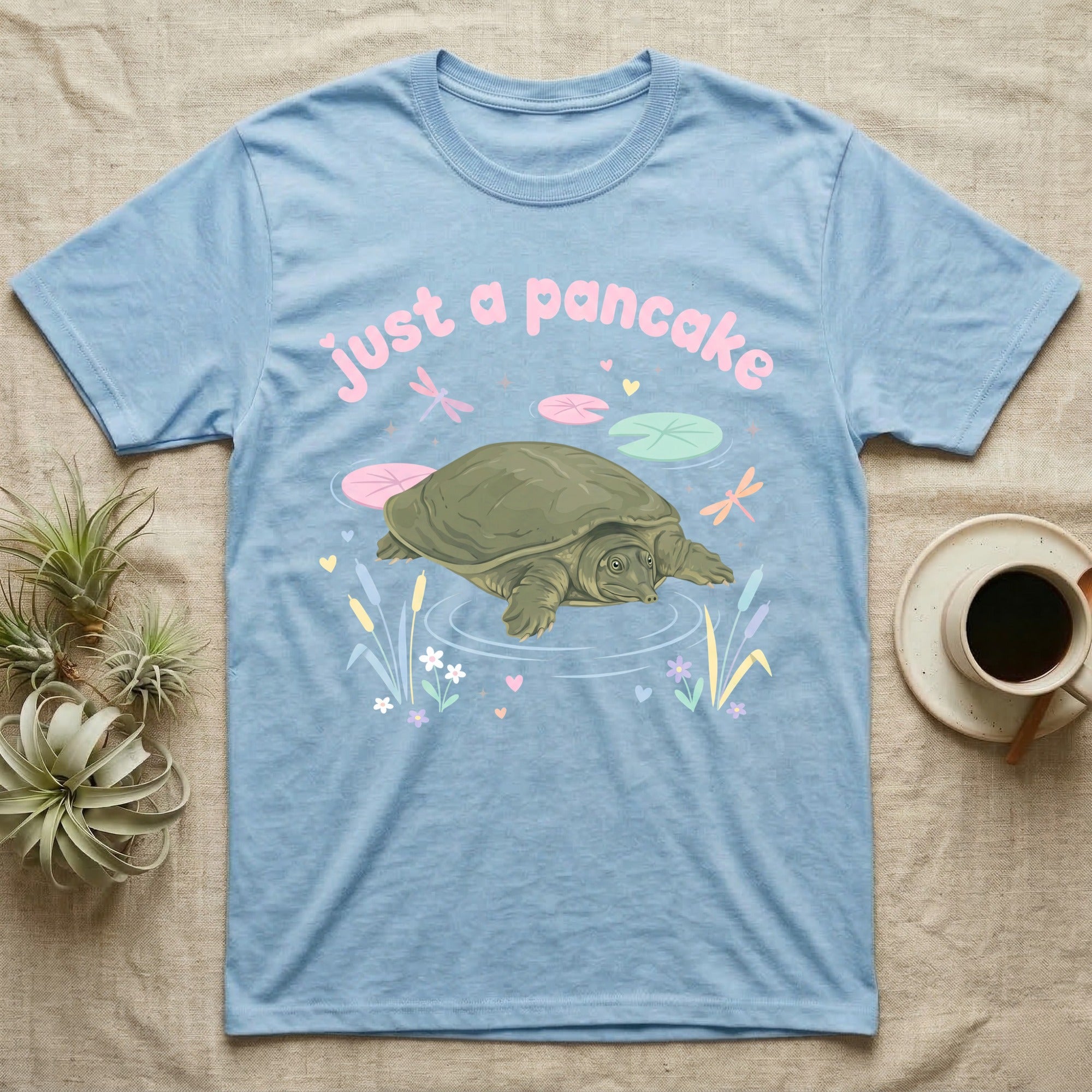 Spiny Softshell Turtle Baby T-Shirt in Light Blue — Pastel spiny softshell turtle with flat shell and snorkel nose among lily pads, puffy pink wordmark "just a pancake" above.