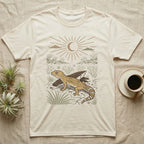 Leopard Gecko Home Range T-Shirt in Natural — Woodcut-style illustration of a leopard gecko standing on cracked earth beside flat stones with thorn scrub behind, no on-shirt text.