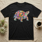 Box Turtle Mosaic T-Shirt in Black — An eastern box turtle on a rising diagonal, its domed shell and legs built from painted watercolour flowers and leaves.