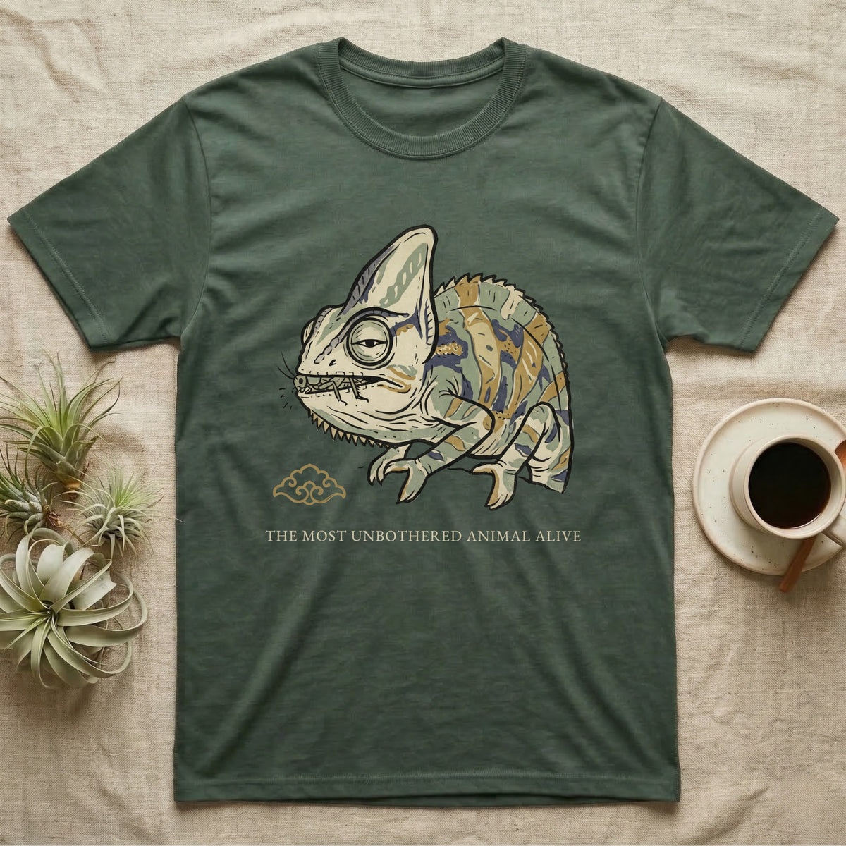 Unbothered Chameleon T-Shirt in Military Green — Ukiyo-e woodblock illustration of a veiled chameleon mid-chew with a deadpan serif caption beneath the subject.
