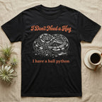 Ball Python Hug T-Shirt in Black — White-line engraving of a coiled ball python under orange script reading I Don't Need a Hug, I have a ball python
