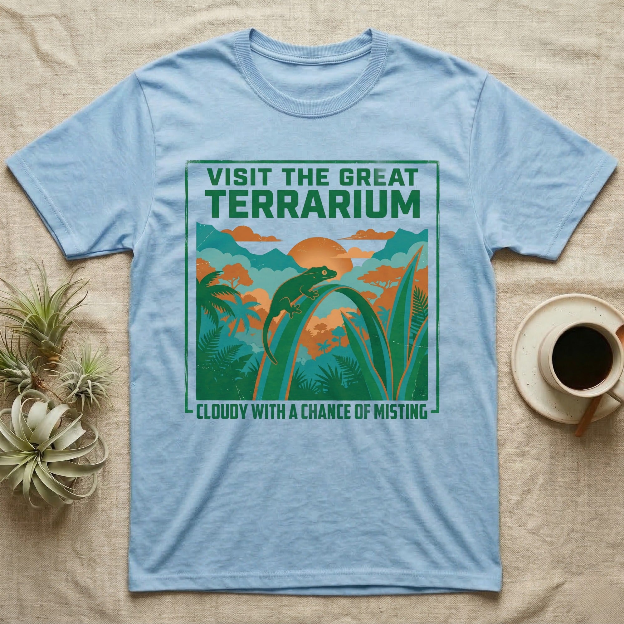 Light blue t-shirt featuring "Visit the Great Terrarium" and "Cloudy with a Chance of Misting" text with jungle scene.