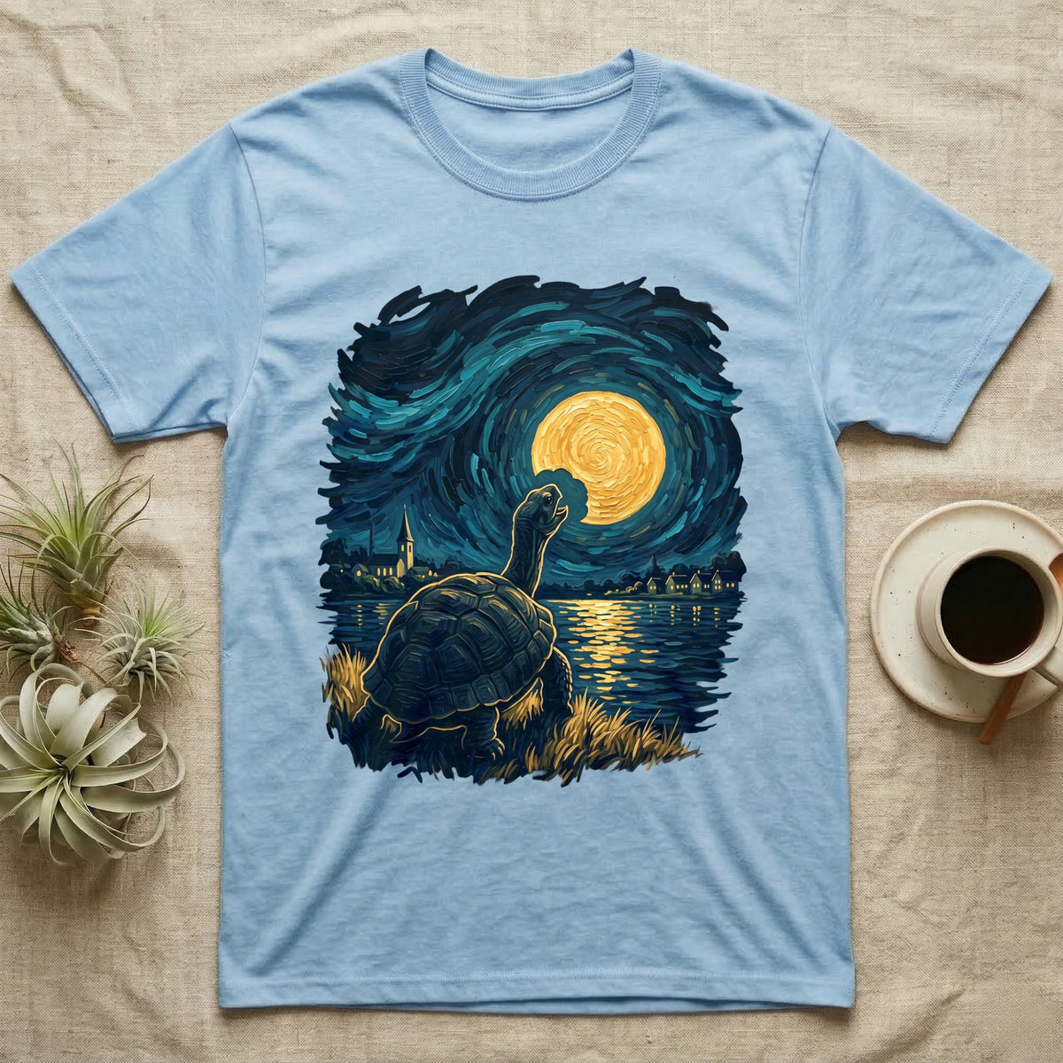 Hermann's Tortoise Moon T-Shirt in Light Blue — Painted Hermann's tortoise seen from behind, neck stretched up, biting a piece out of a golden spiral moon in a swirling blue night sky over a lake