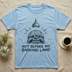 Russian Tortoise Mornings T-Shirt in Light Blue — Charcoal drawing of a grumpy Russian tortoise yelling up at a basking lamp above the words NOT BEFORE MY BASKING LAMP.