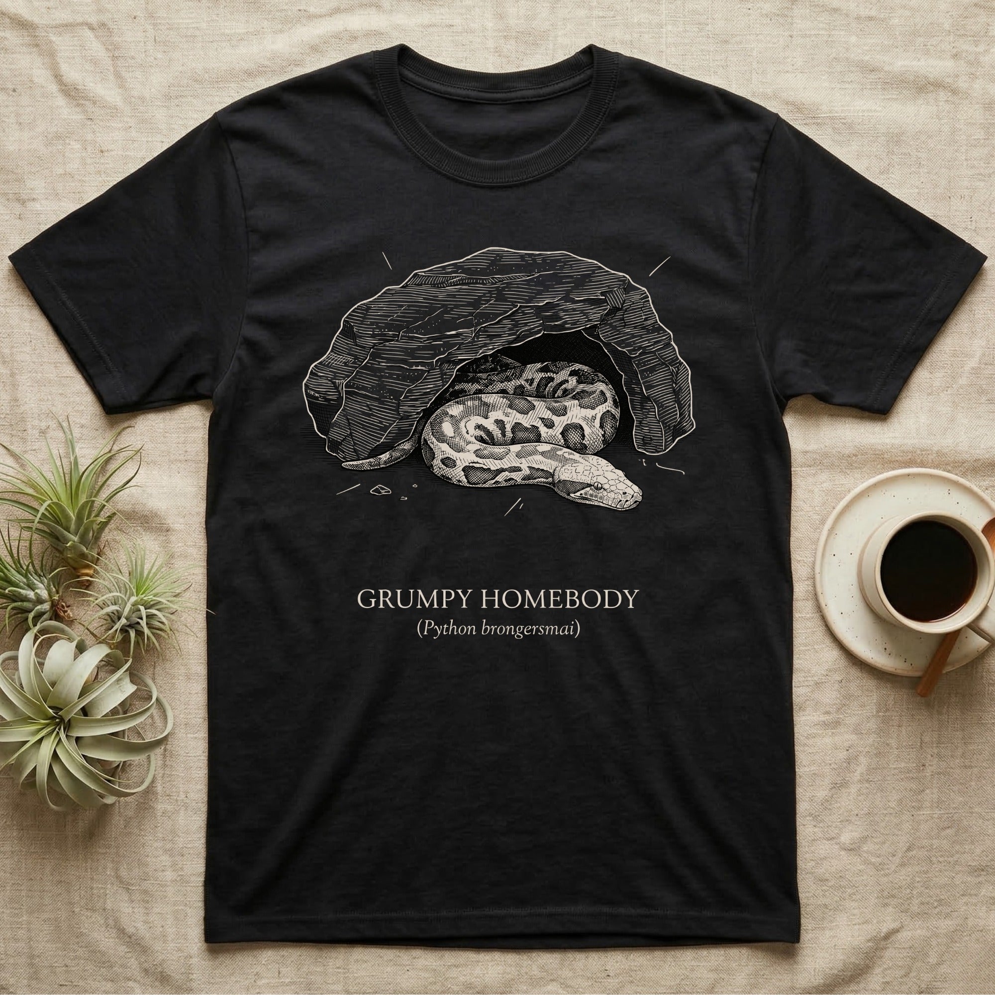Blood Python Grumpy Homebody T-Shirt in Black — Naturalist ink engraving of a blood python resting in a rock cave, captioned "Grumpy Homebody, Python brongersmai".