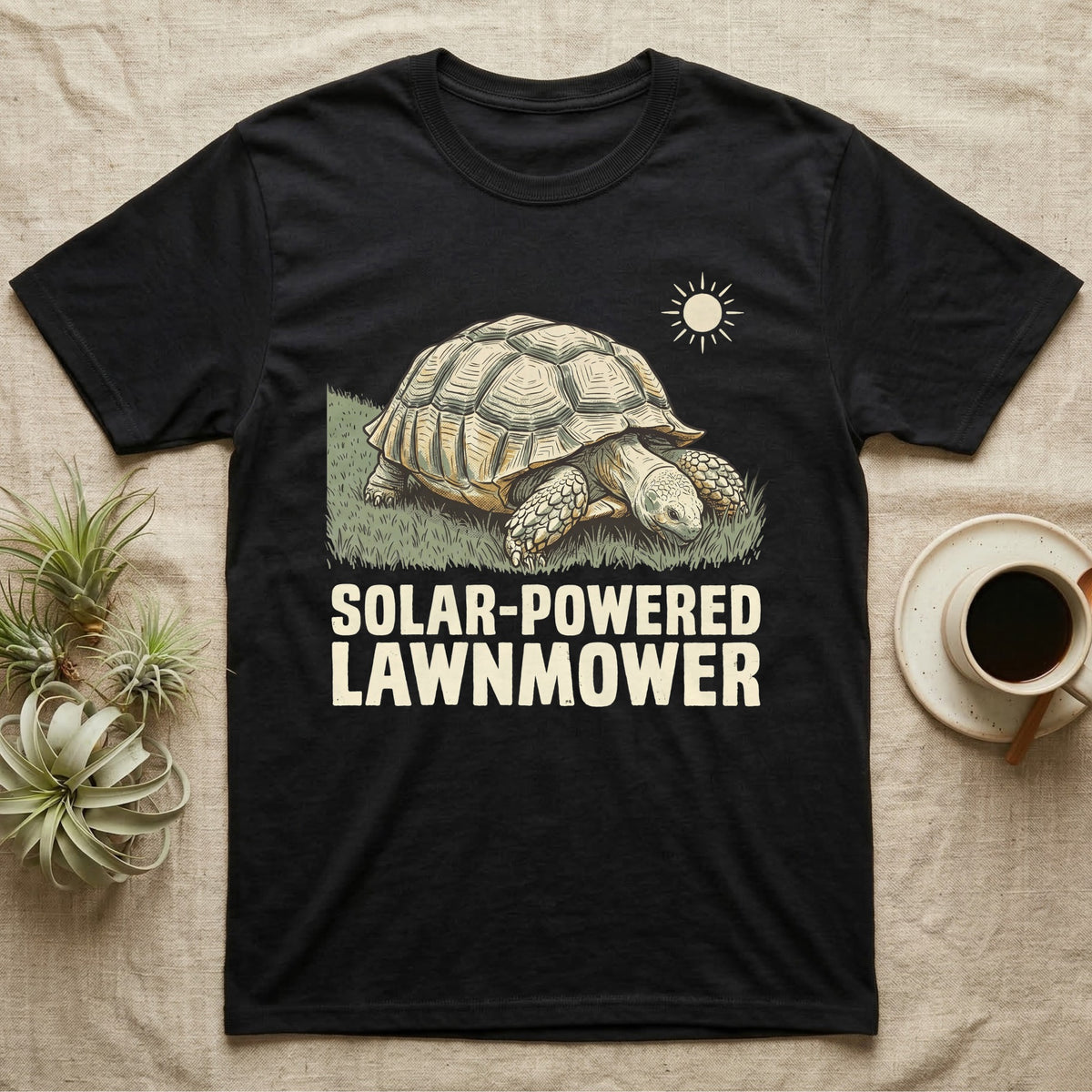 Solar Powered Lawnmower T-Shirt in Black — Retro-illustration of a sulcata tortoise grazing a lawn stripe under a sun motif with a Solar-Powered Lawnmower caption.