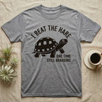 Red-Foot Tortoise Bragging T-Shirt in Sport Grey — Smug red-footed tortoise walking chin-up under I Beat the Hare, One Time, Still Bragging