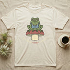 Cream t-shirt with a frog sitting on a mushroom, text "let me be weird in peace".
