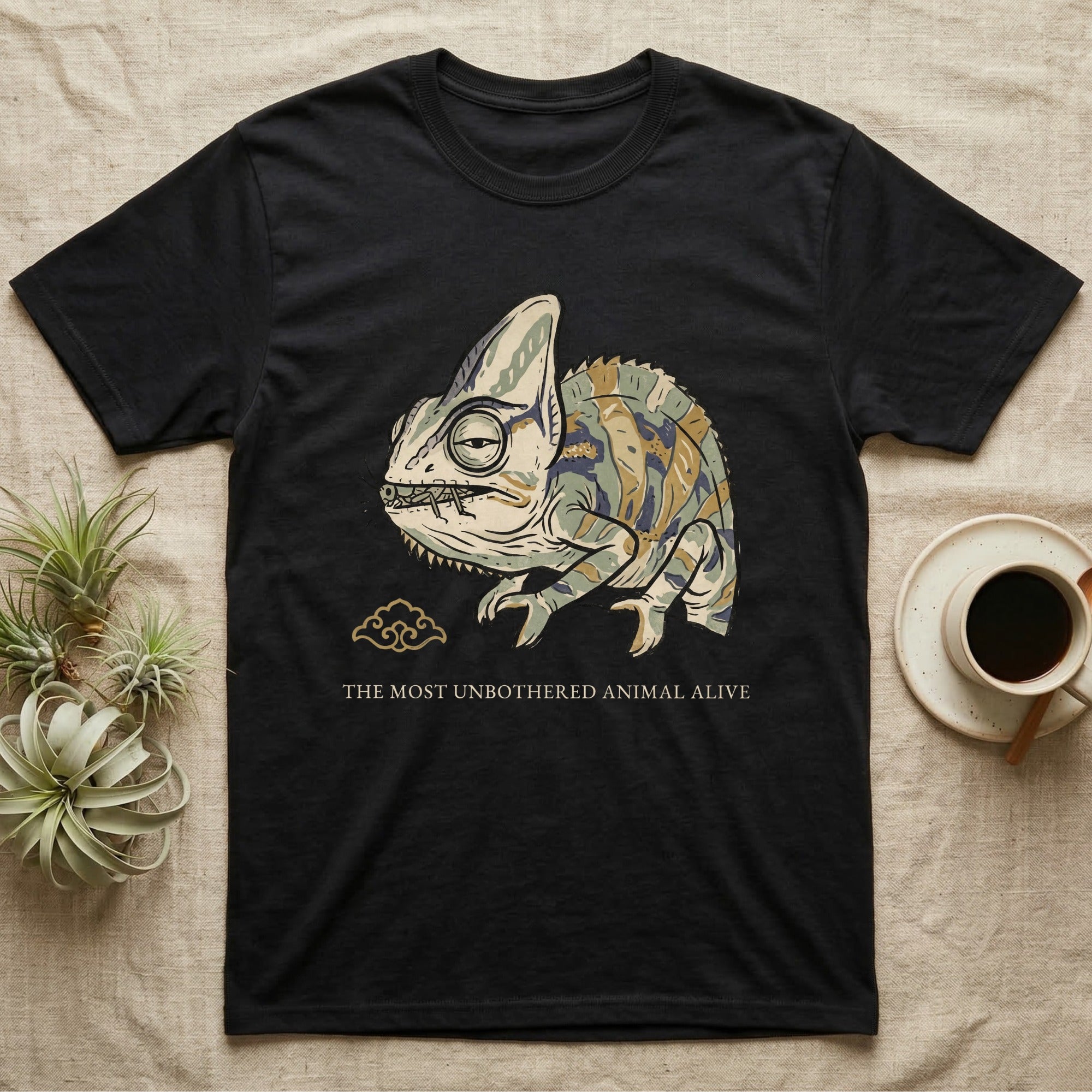 Unbothered Chameleon T-Shirt in Black — Ukiyo-e woodblock illustration of a veiled chameleon mid-chew with a deadpan serif caption beneath the subject.