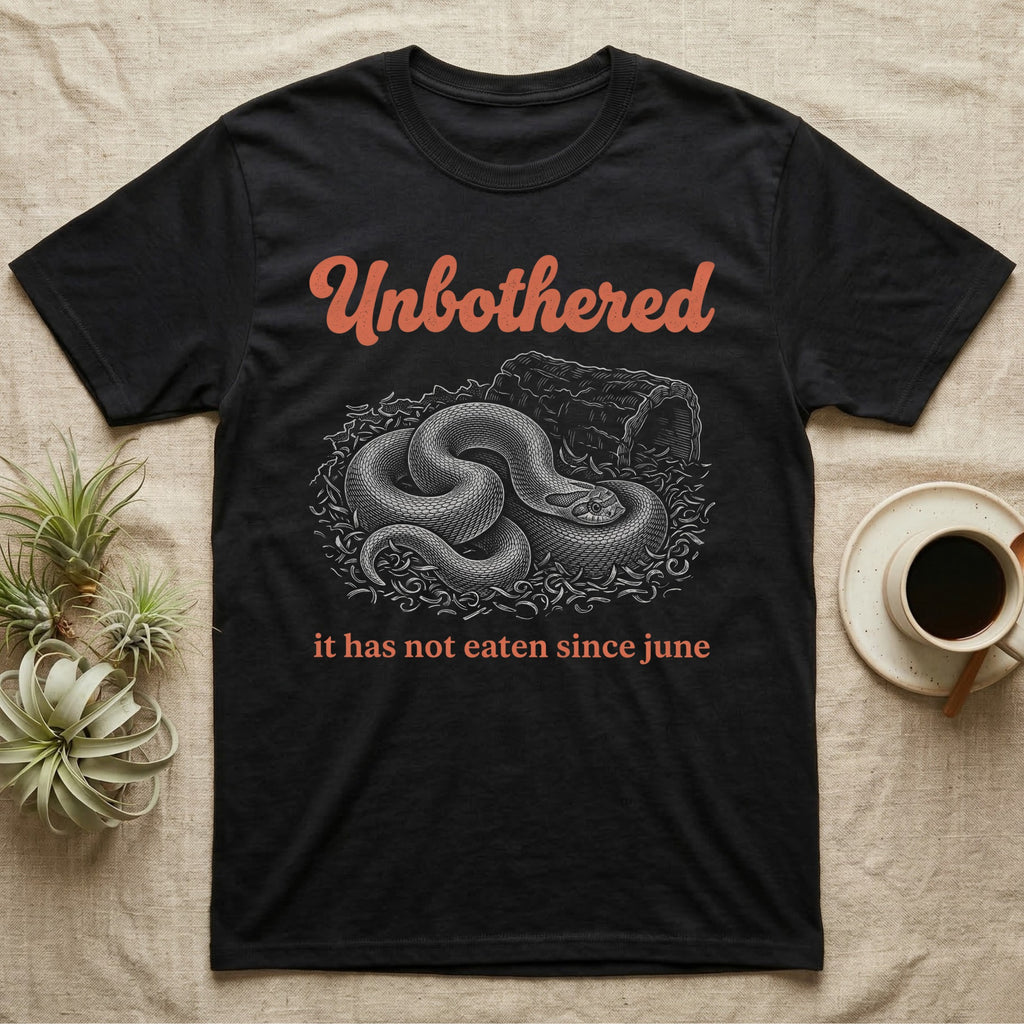 Western Hognose Unbothered T-Shirt in Black — White engraved western hognose snake coiled in loose substrate beside a hide, under the word Unbothered and above it has not eaten since june.